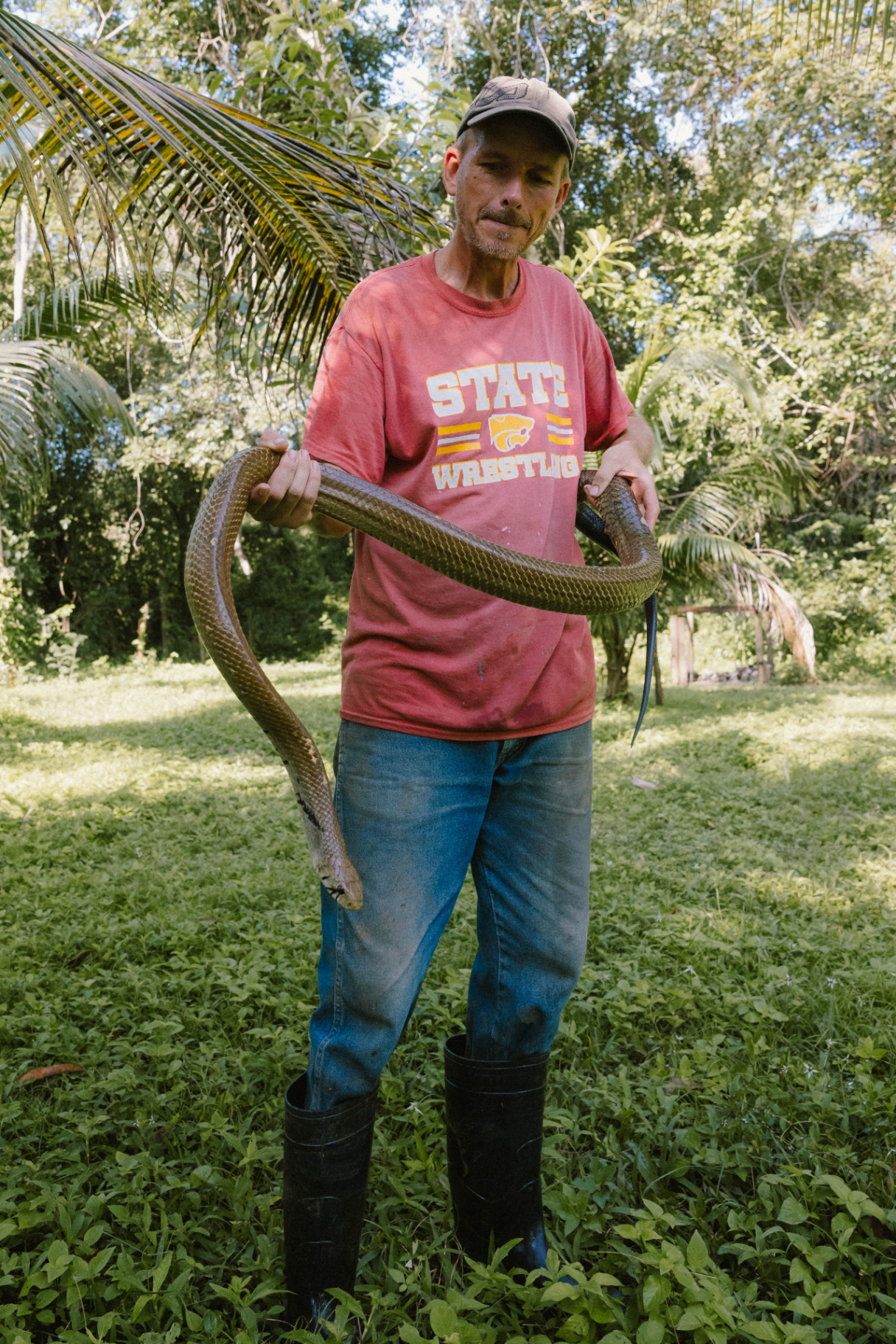 The author holding a large snake in a sunny Belize jungle clearing.